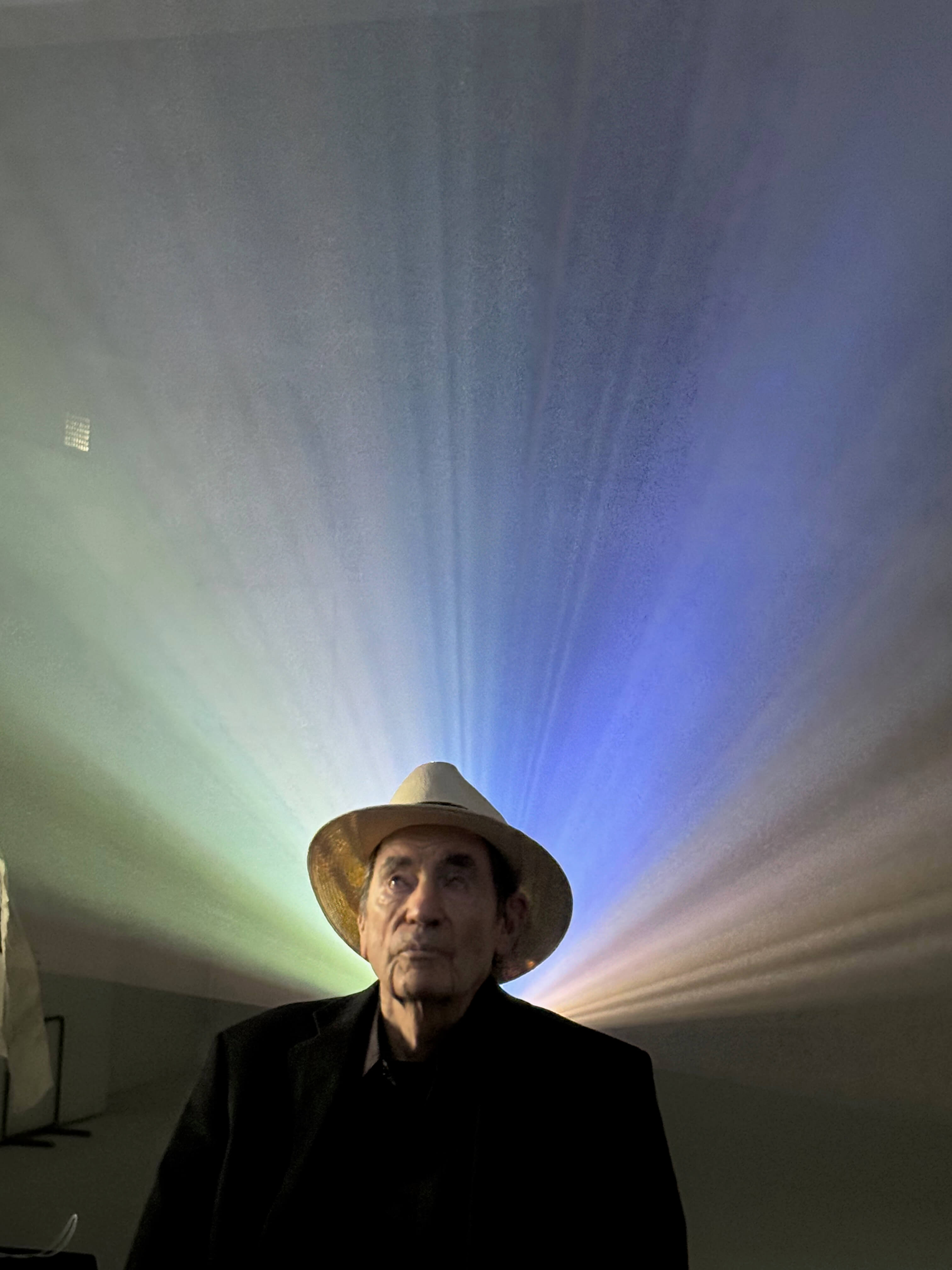 Albie awith colour from projections of archival footage behind him