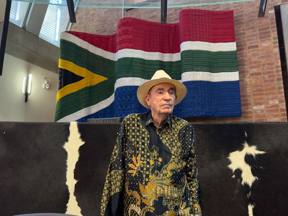 Albie in ConCourt main court chamber with beaded flag and cow hides in background.